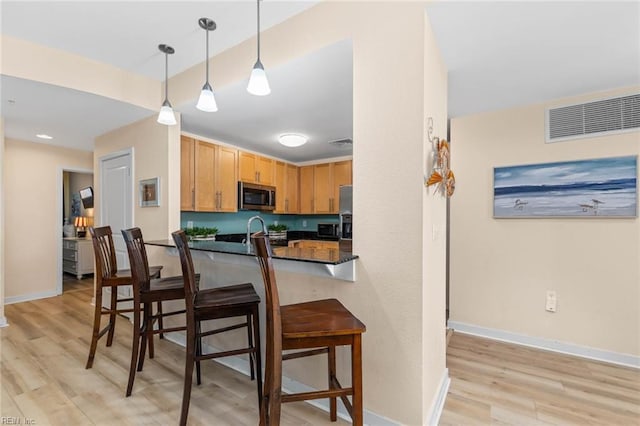 kitchen with visible vents, a kitchen breakfast bar, range, stainless steel microwave, and dark countertops