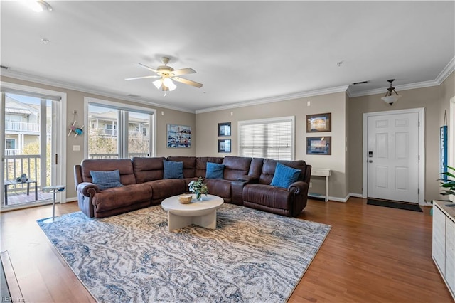 living room with ceiling fan, crown molding, baseboards, and wood finished floors