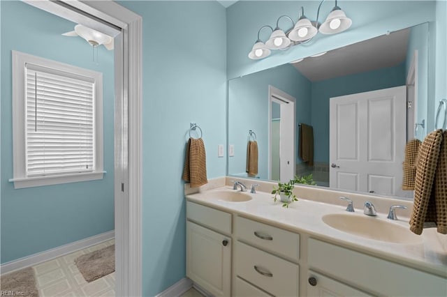 full bathroom with double vanity, a sink, and baseboards