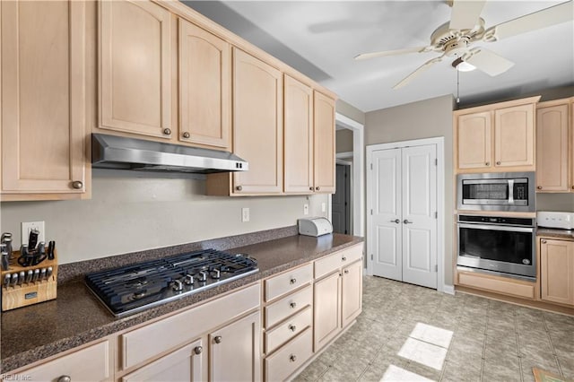 kitchen with dark countertops, under cabinet range hood, stainless steel appliances, and light brown cabinetry