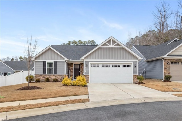 craftsman inspired home with fence, an attached garage, concrete driveway, stone siding, and board and batten siding