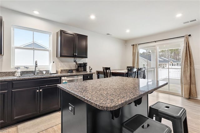 kitchen with a center island, a breakfast bar, light wood-type flooring, and a sink