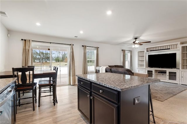 kitchen featuring visible vents, light stone counters, a kitchen breakfast bar, stainless steel dishwasher, and light wood-style floors