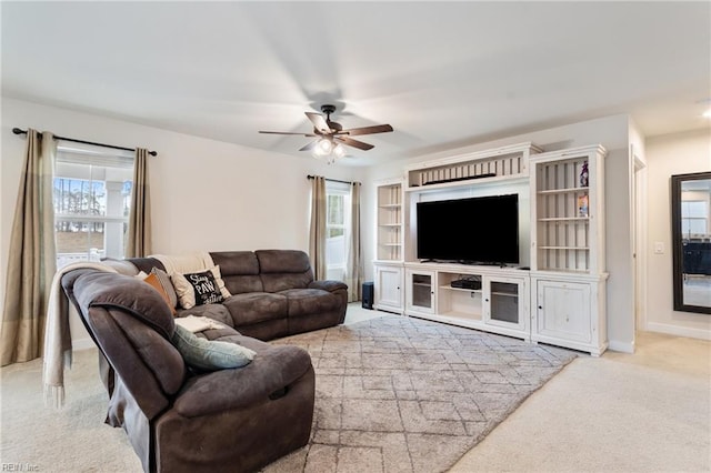 carpeted living room featuring baseboards, a healthy amount of sunlight, and a ceiling fan