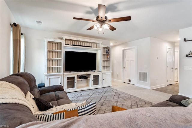 living room with light carpet, visible vents, baseboards, and a ceiling fan