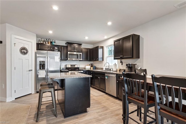 kitchen with visible vents, light wood-type flooring, a breakfast bar, a sink, and appliances with stainless steel finishes