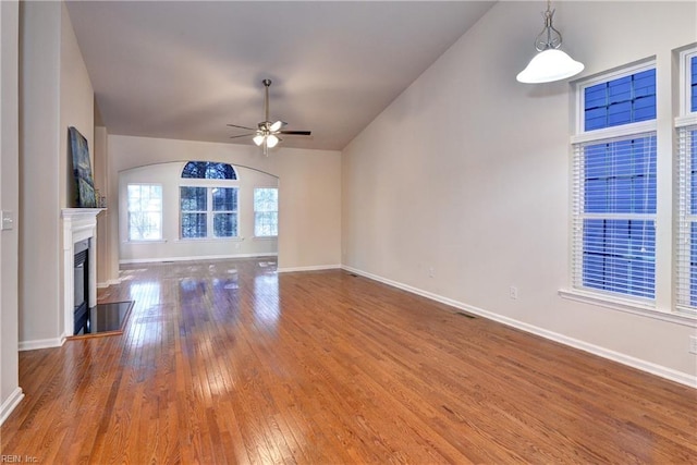 unfurnished living room featuring baseboards, lofted ceiling, hardwood / wood-style flooring, ceiling fan, and a high end fireplace