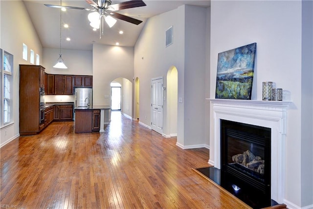 kitchen featuring arched walkways, dark countertops, visible vents, freestanding refrigerator, and a glass covered fireplace