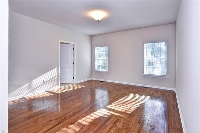 spare room featuring baseboards and hardwood / wood-style floors