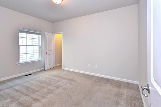 carpeted spare room featuring visible vents and baseboards