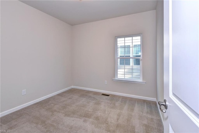 spare room with carpet floors, visible vents, and baseboards