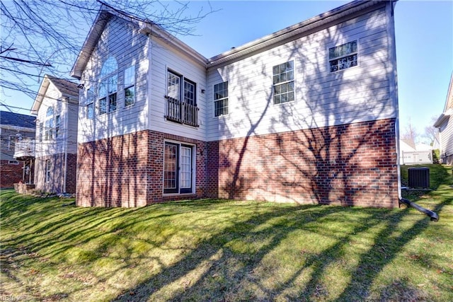 rear view of property featuring central air condition unit, a lawn, and brick siding