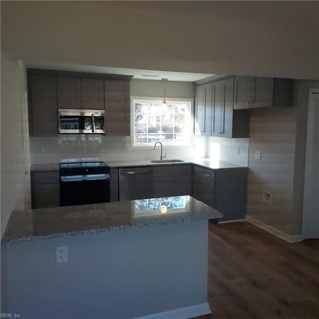 kitchen with light stone counters, black range with electric cooktop, a sink, dishwasher, and stainless steel microwave