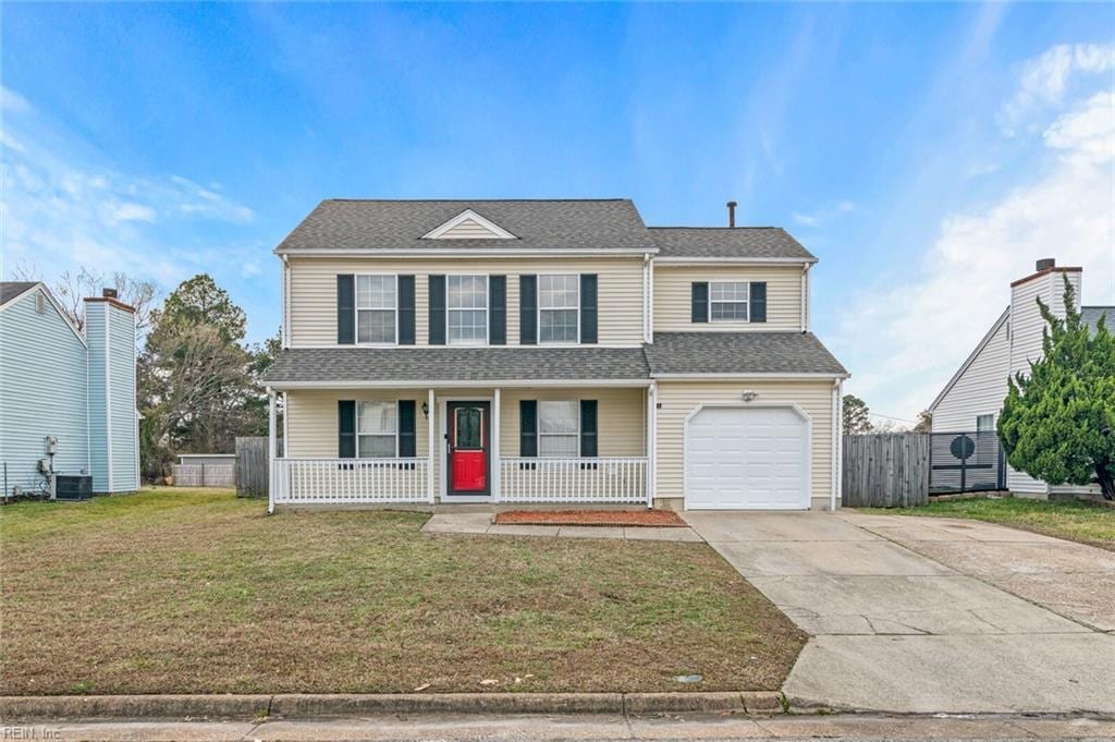 traditional-style house with covered porch, concrete driveway, a front yard, a garage, and cooling unit