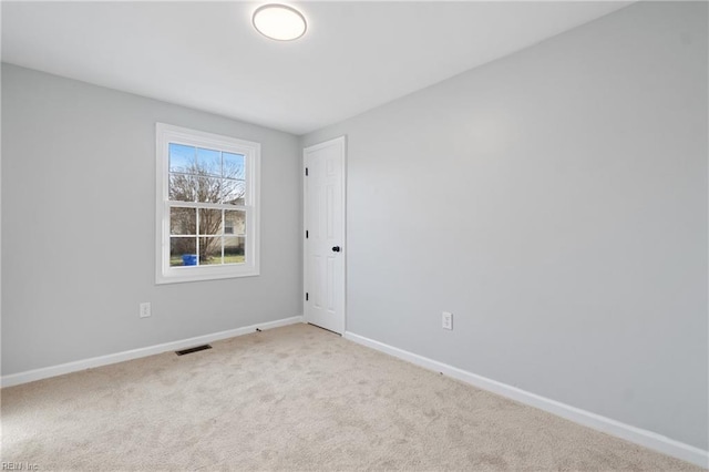 empty room with carpet, visible vents, and baseboards