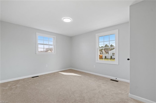 spare room featuring carpet, visible vents, and baseboards