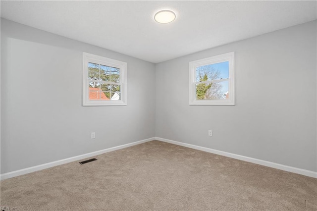 carpeted empty room featuring visible vents and baseboards