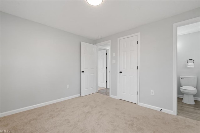 unfurnished bedroom with carpet floors, connected bathroom, and baseboards