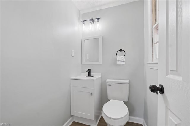 bathroom with wood finished floors, vanity, toilet, and baseboards