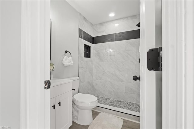 full bathroom with tiled shower, vanity, and toilet