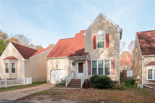 traditional-style home with concrete driveway, an attached garage, fence, and central air condition unit