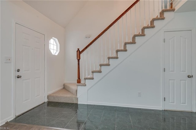 entryway with lofted ceiling, tile patterned flooring, stairs, and baseboards