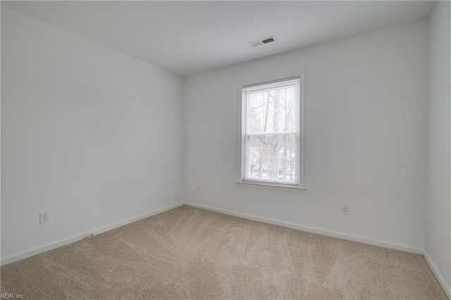 spare room with light carpet, baseboards, and visible vents