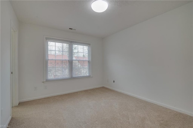 spare room featuring light carpet, baseboards, and visible vents