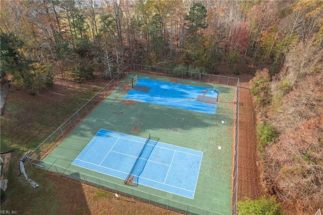 view of basketball court with a tennis court and fence