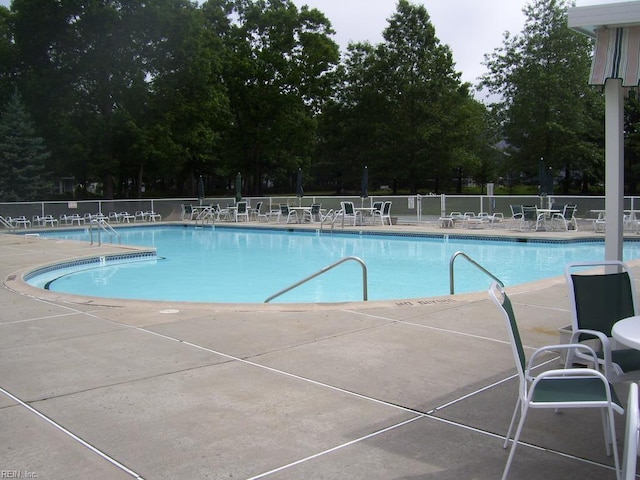 community pool with fence and a patio