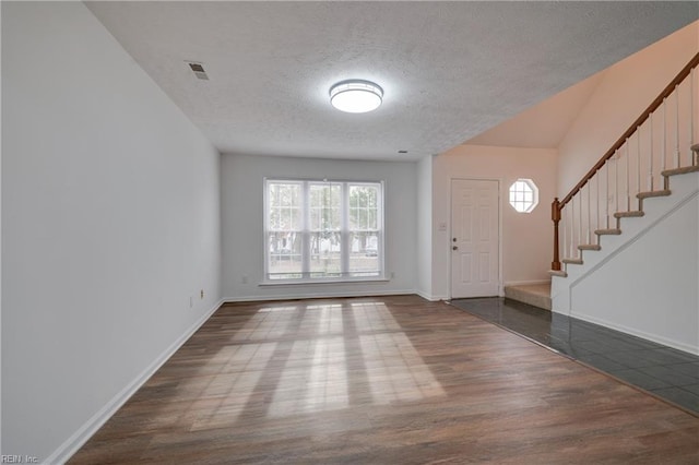 entrance foyer featuring stairs, visible vents, baseboards, and wood finished floors