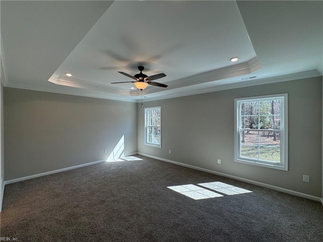 empty room with visible vents, a tray ceiling, a wealth of natural light, and baseboards