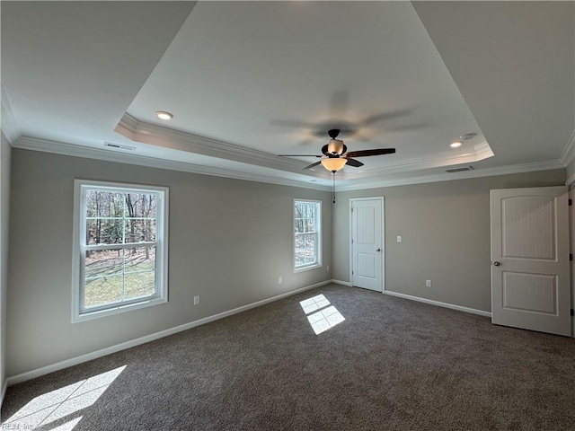 empty room with ornamental molding, a tray ceiling, carpet, and baseboards