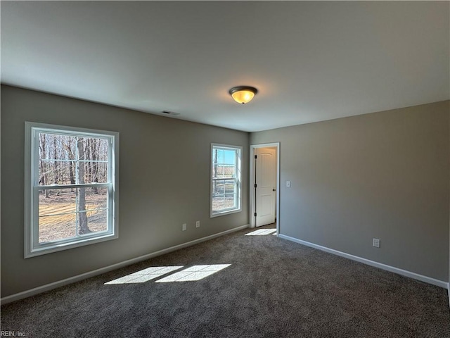 empty room with carpet flooring, visible vents, and baseboards