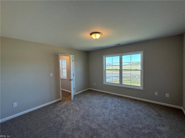 carpeted spare room featuring visible vents and baseboards