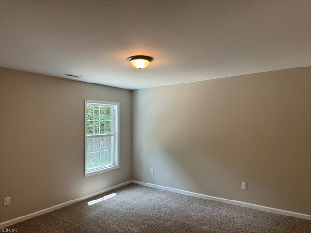carpeted spare room featuring visible vents and baseboards