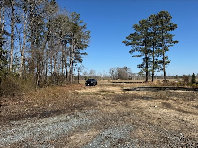 view of yard with dirt driveway, a carport, and a rural view