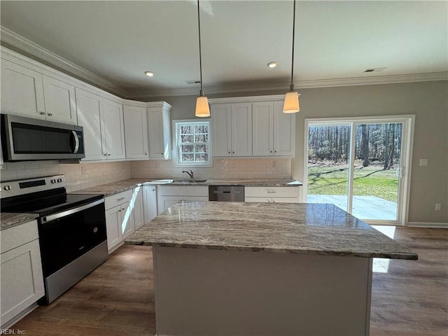 kitchen with appliances with stainless steel finishes, backsplash, white cabinetry, and crown molding