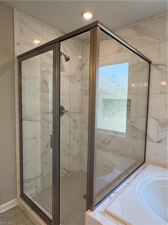 bathroom featuring baseboards, a garden tub, and a shower stall