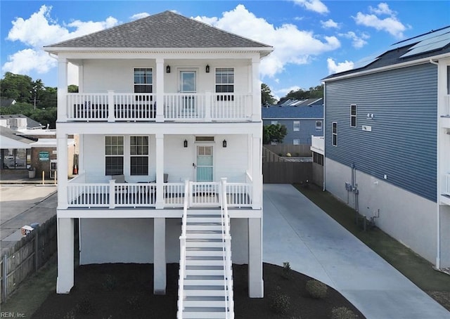 view of front of home featuring covered porch, roof with shingles, fence, and stairs