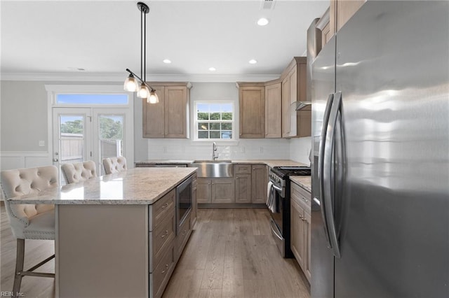 kitchen with appliances with stainless steel finishes, a center island, crown molding, and a kitchen breakfast bar