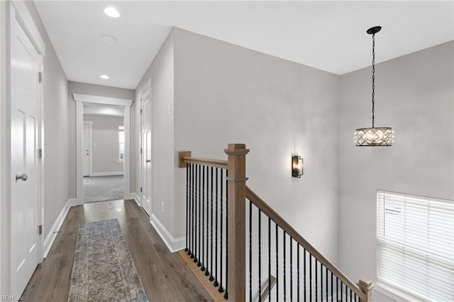 hallway with recessed lighting, baseboards, dark wood finished floors, and an upstairs landing