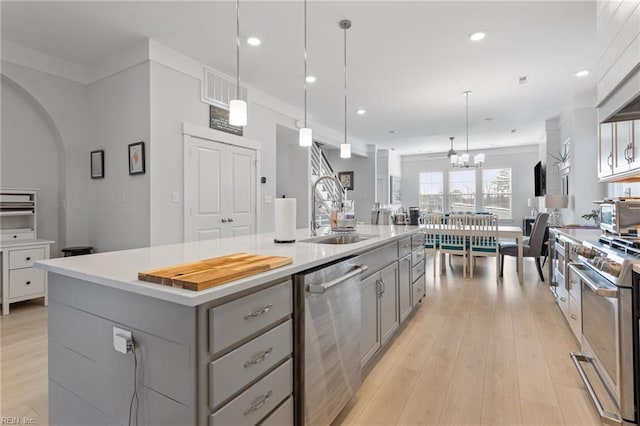 kitchen featuring light wood finished floors, visible vents, stainless steel appliances, gray cabinets, and a sink