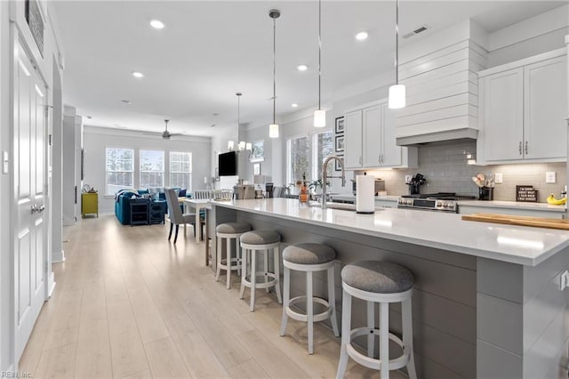 kitchen featuring light wood-style floors, tasteful backsplash, visible vents, and open floor plan