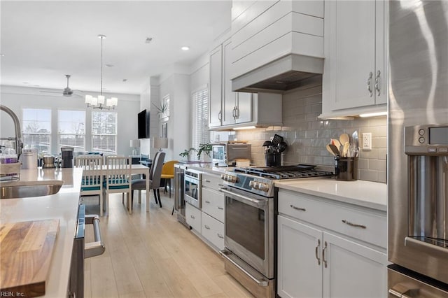 kitchen featuring a sink, light countertops, appliances with stainless steel finishes, decorative backsplash, and custom range hood