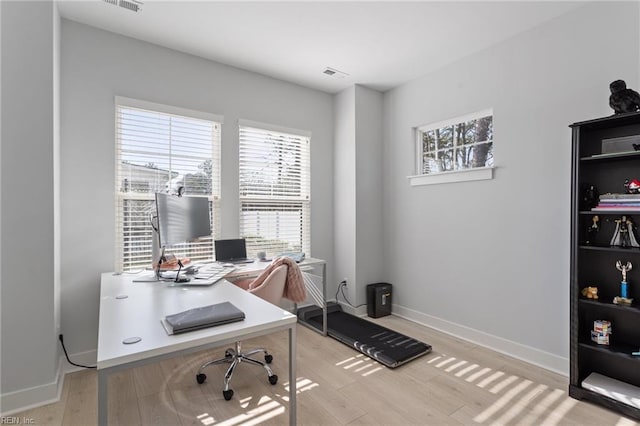 office space with light wood-style floors, a wealth of natural light, and baseboards