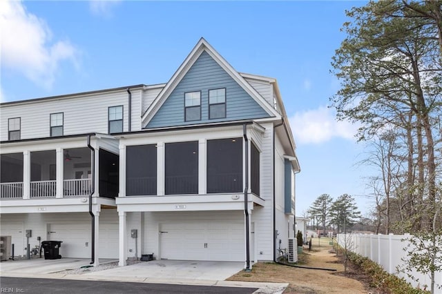 back of property with driveway, central AC unit, a sunroom, an attached garage, and fence