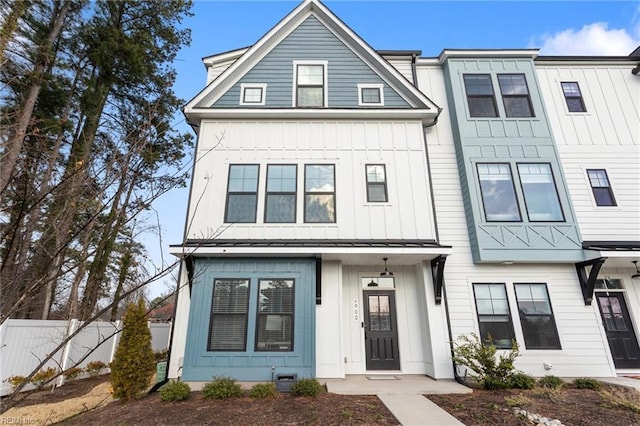 townhome / multi-family property featuring a standing seam roof, metal roof, board and batten siding, and fence