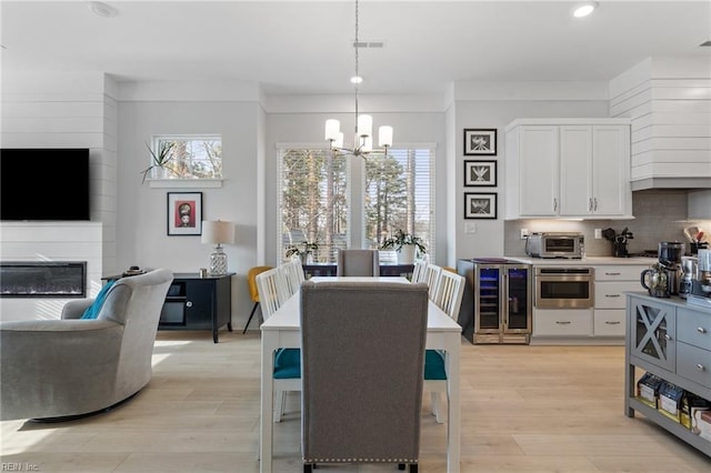 kitchen featuring light wood finished floors, a toaster, white cabinets, decorative backsplash, and wine cooler