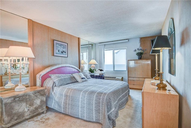 bedroom featuring a textured ceiling, carpet flooring, and wooden walls